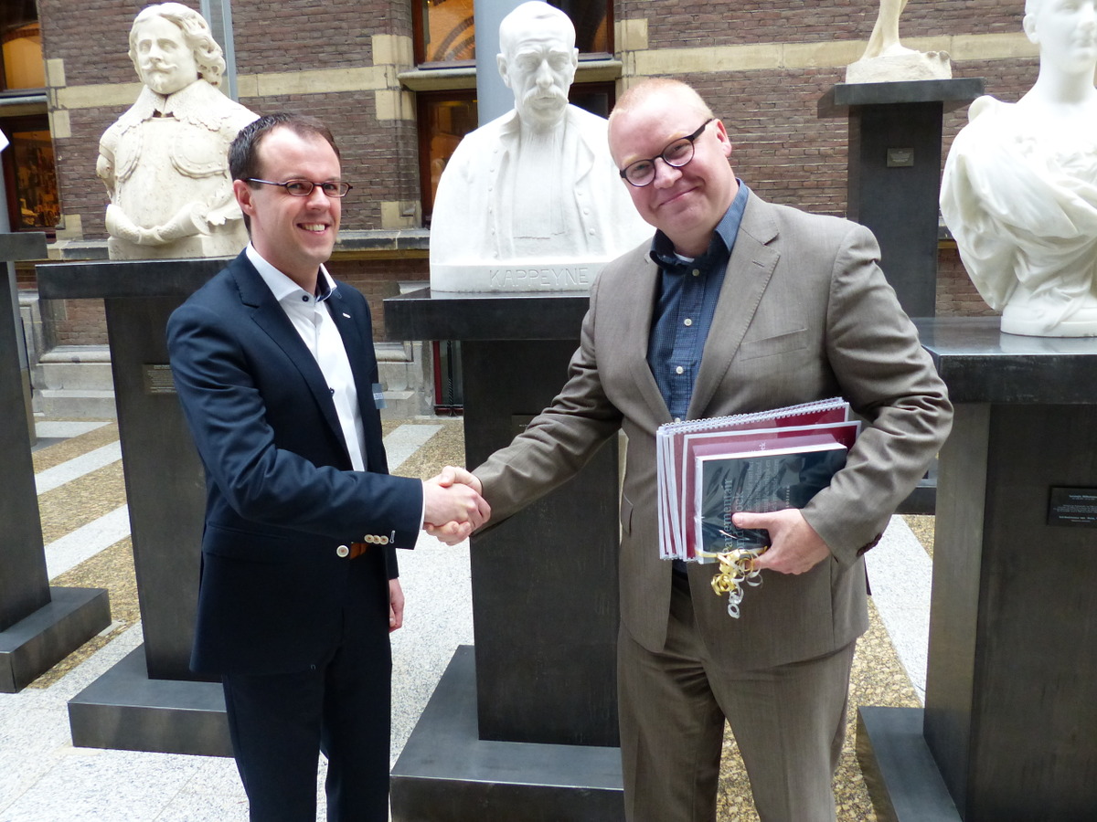 Aanbieding 1e exemplaar MI-policy paper door Sandor Loeffen aan Roland van Vliet 